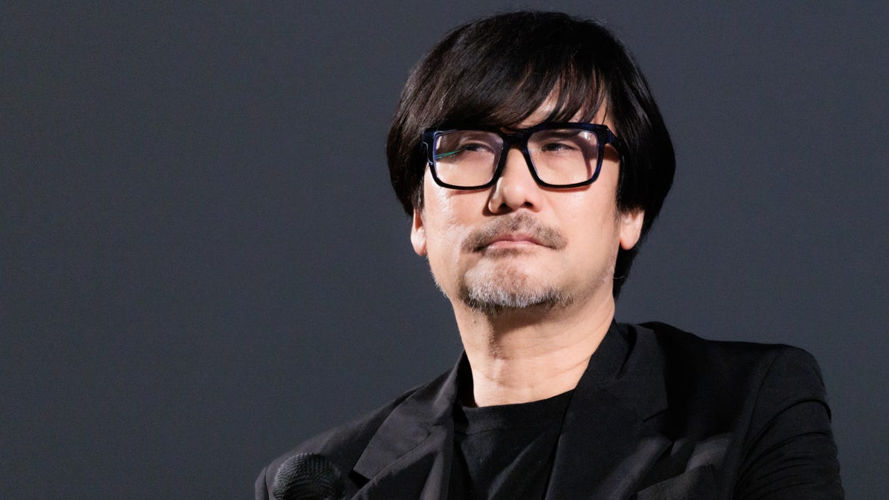 Hideo Kojima blickt ernst in die Kamera während einer Bühnenpräsentation