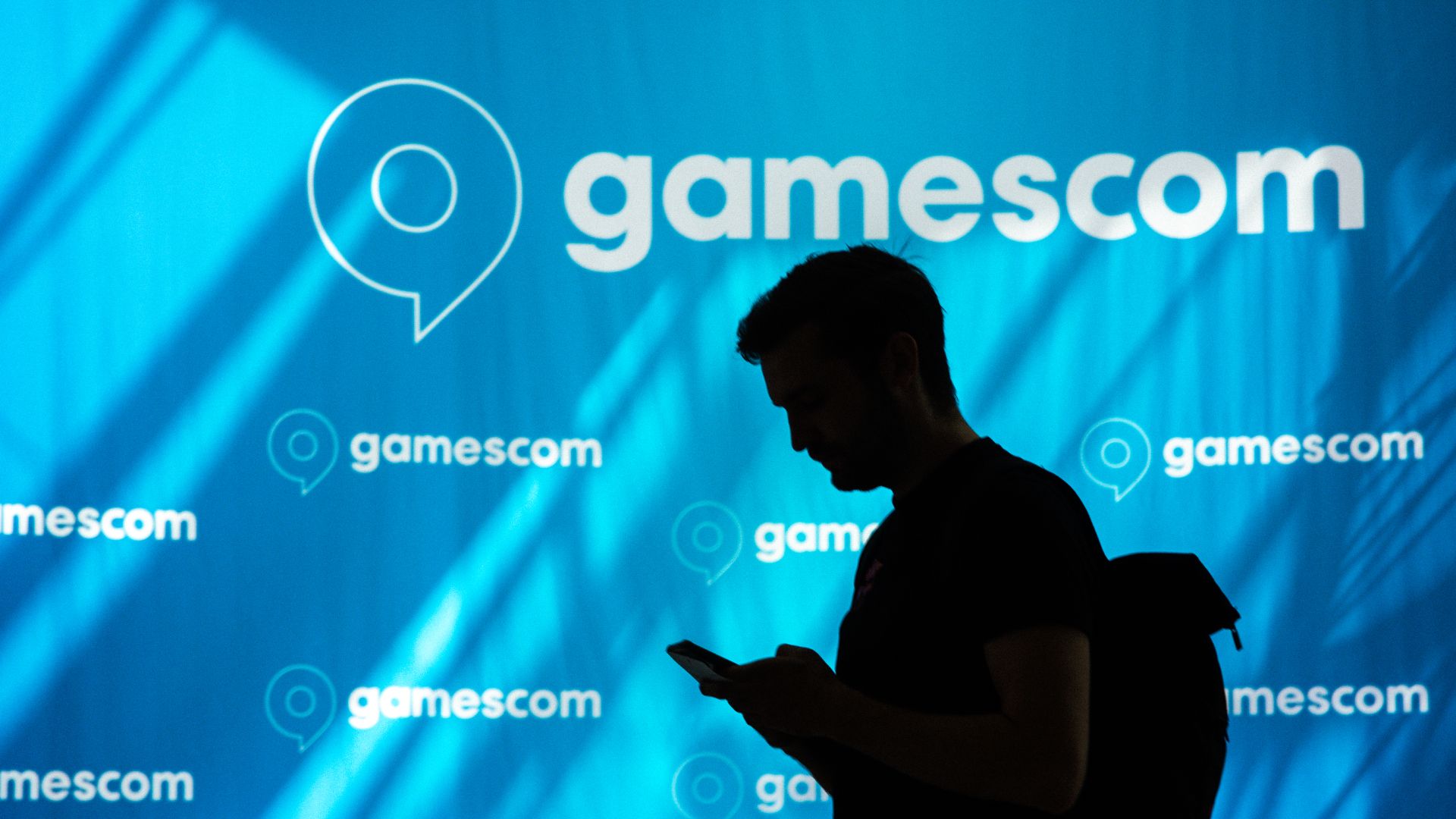 Silhouette eines Besuchers vor einer gamescom-Werbewand mit Logo